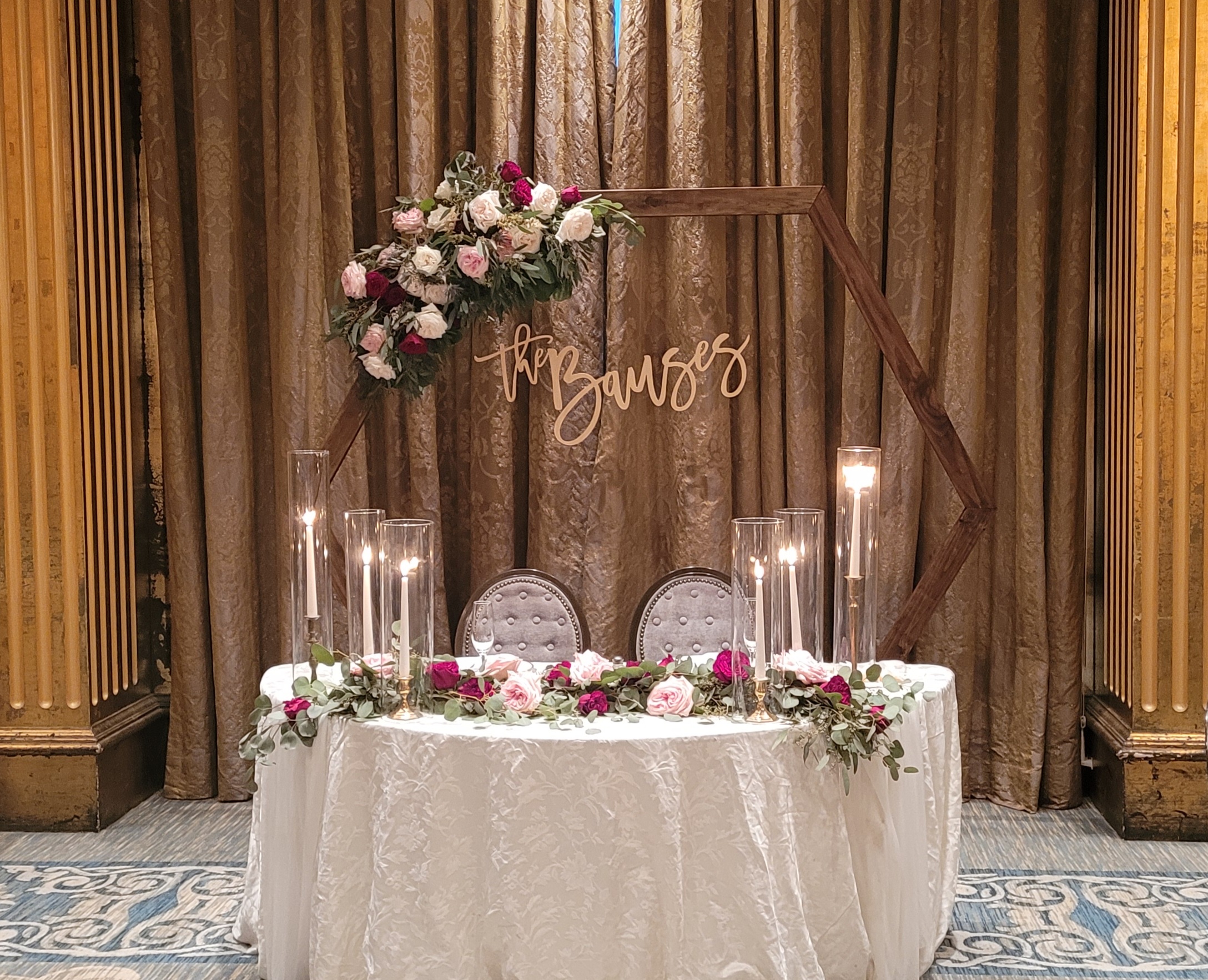 bride and groom's table at wedding reception with wooden hexagon arch backdrop