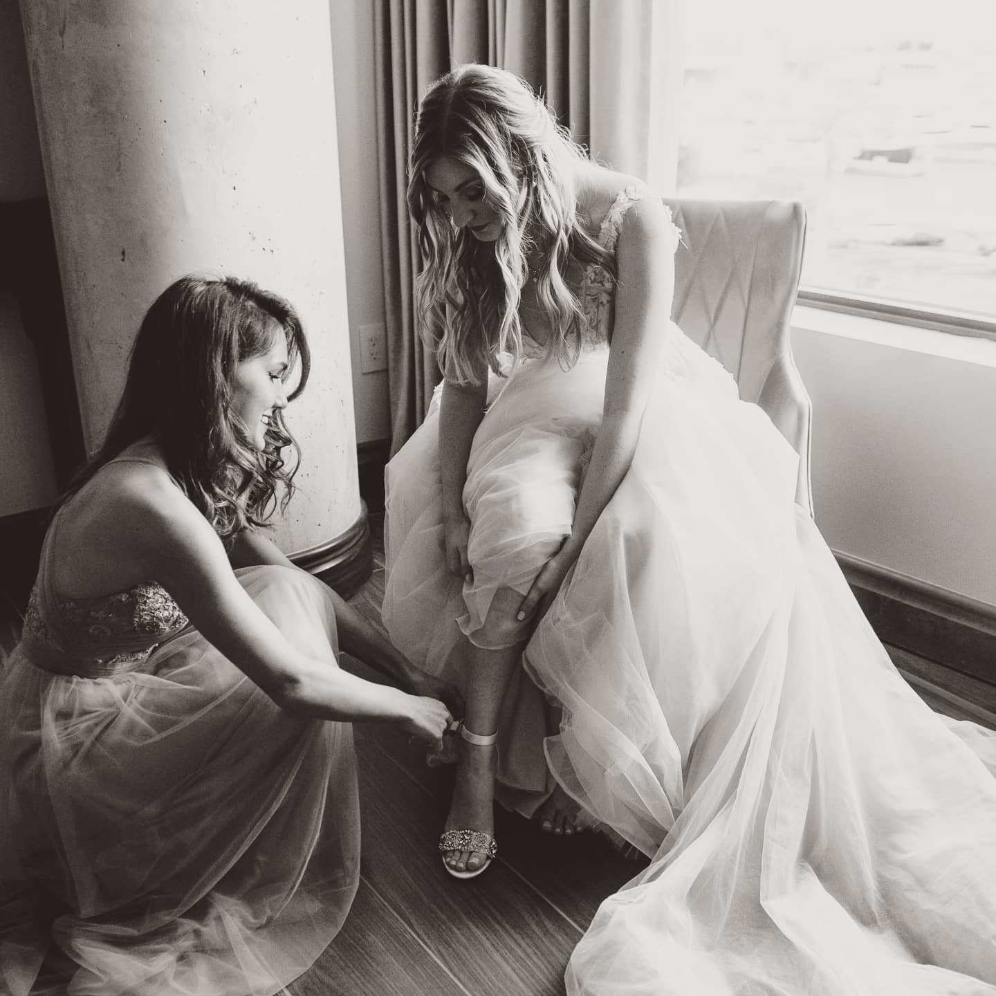 bridesmaid helping pride put shoes on