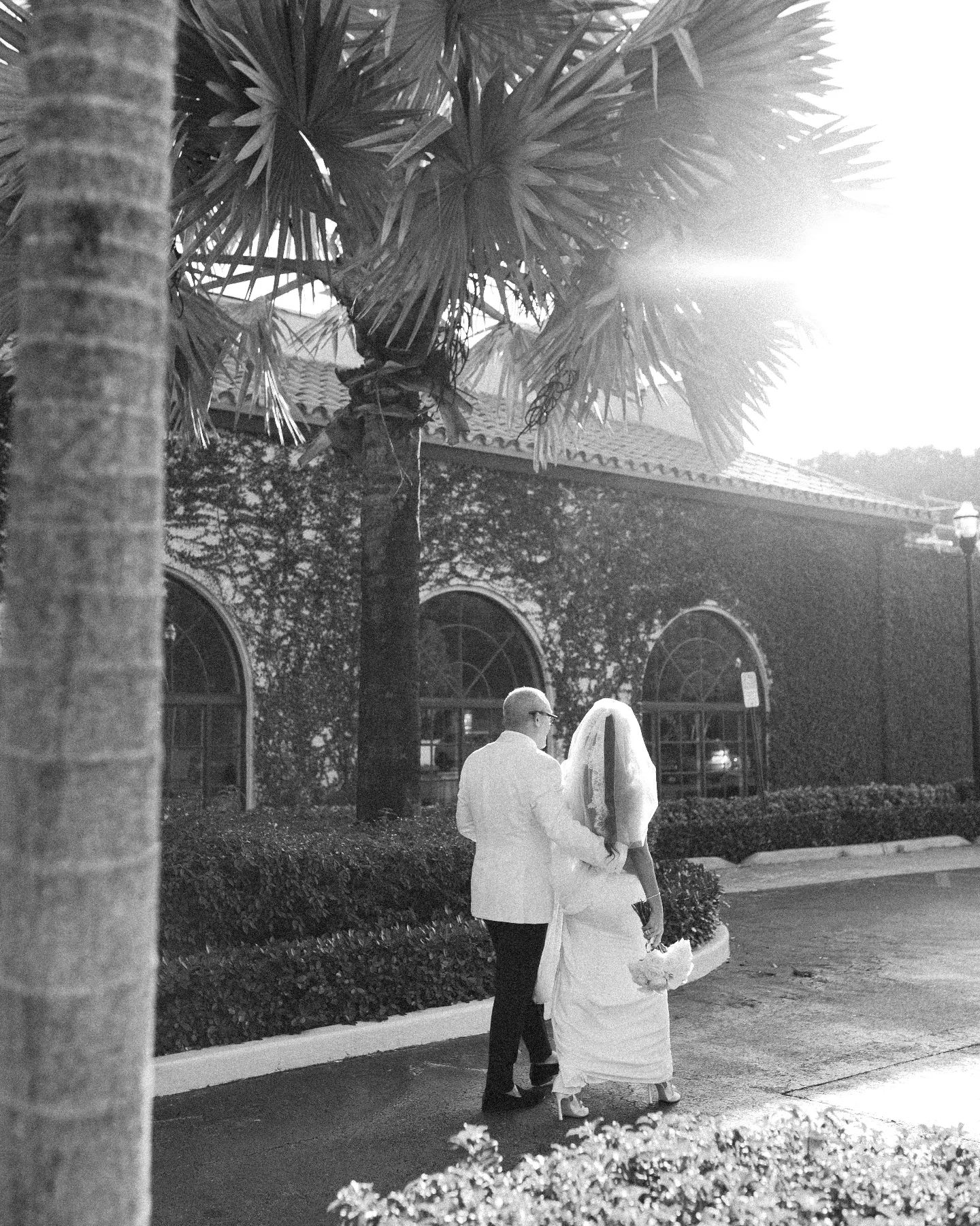 bride and groom walking together with groom's arm around her waist