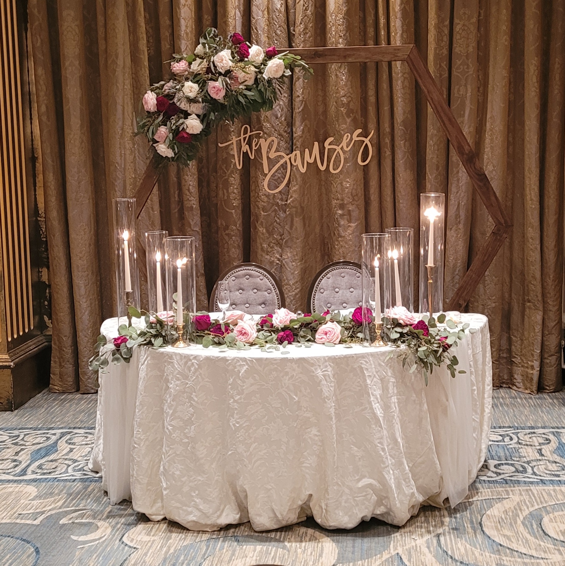 couple reception table with white and pink roses and modern arch