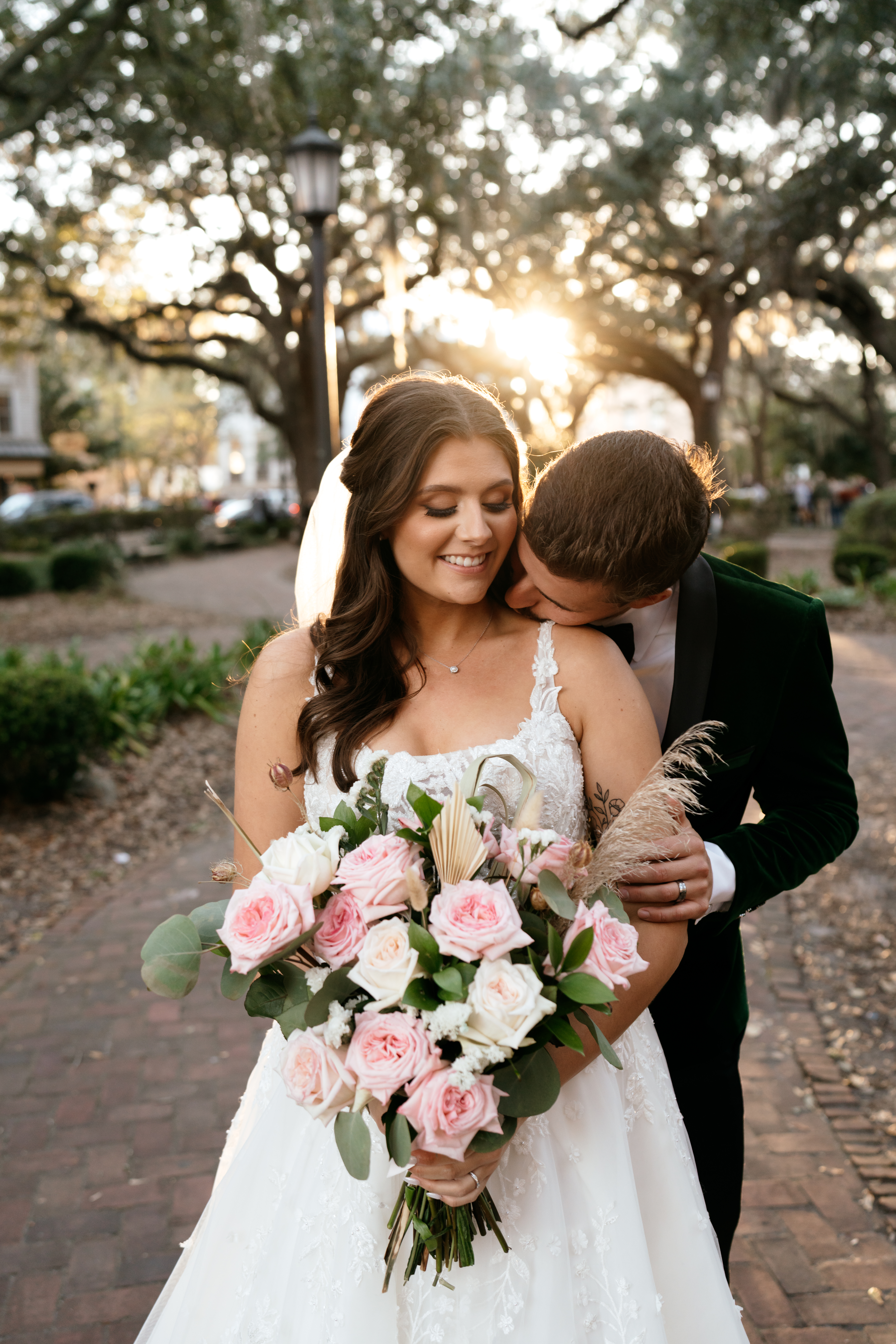 groom kissing bride with pink bouquet