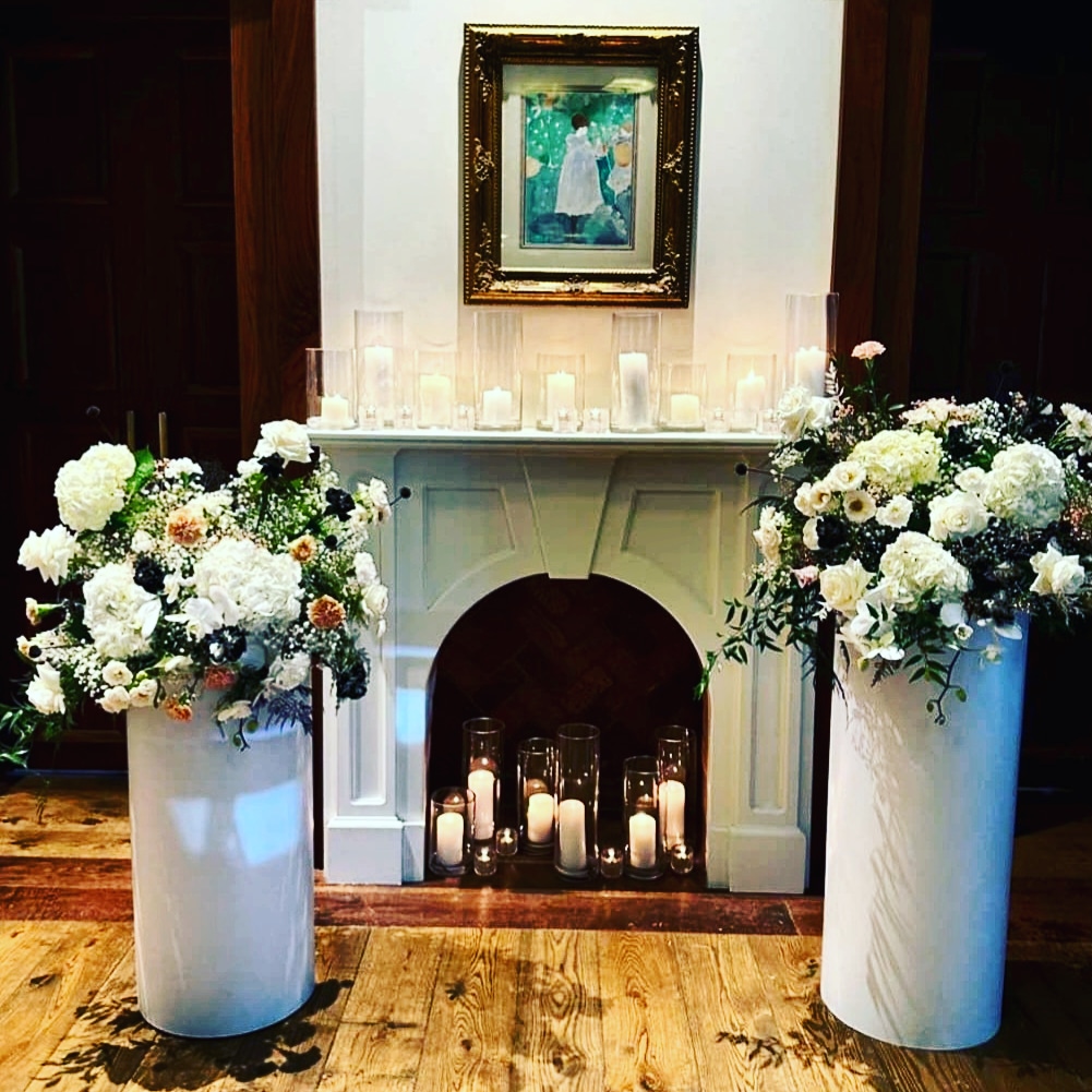 fireplaced lined with candles and surrounded by white flower bouquets