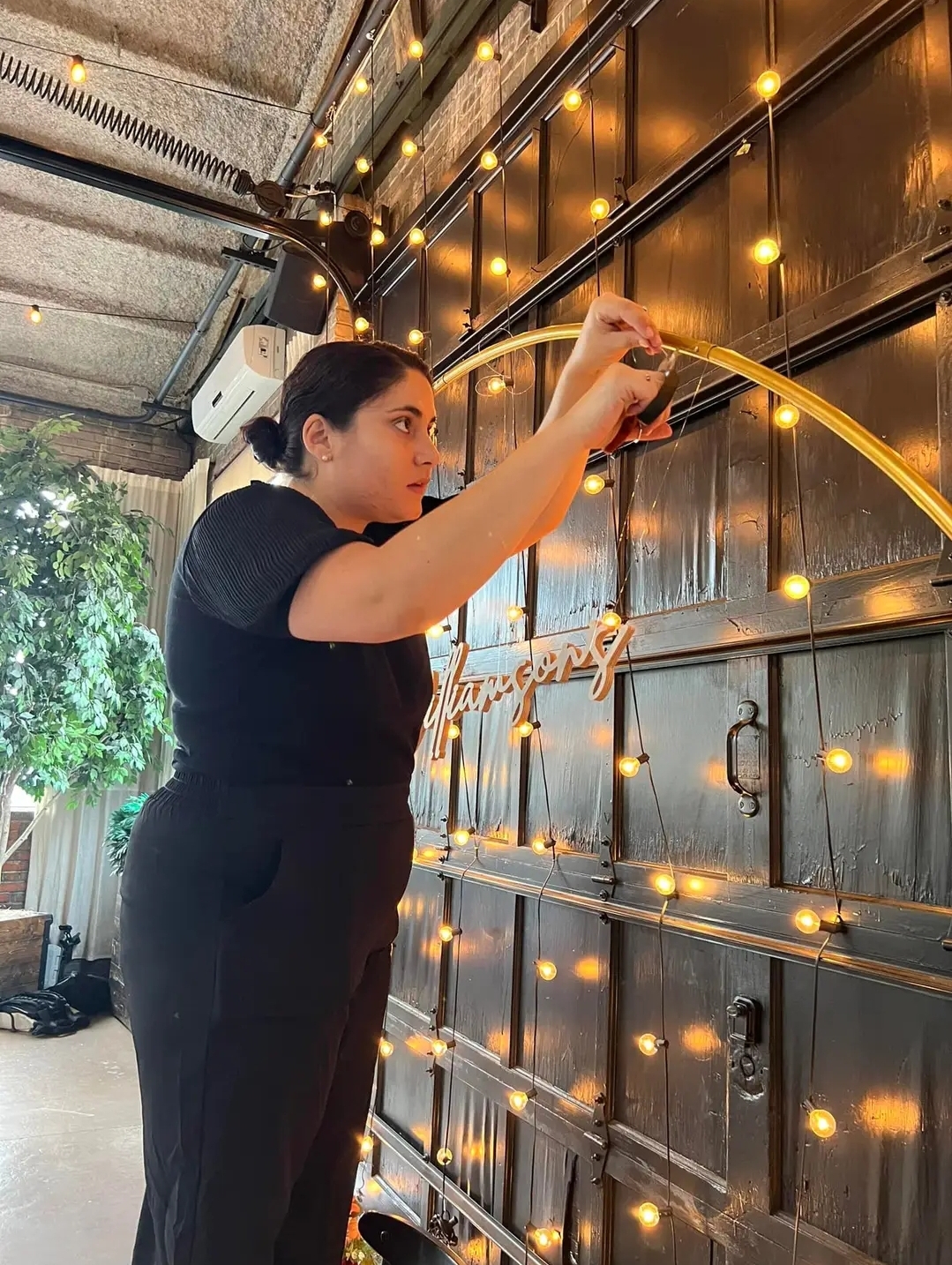 woman tying off lights to sign