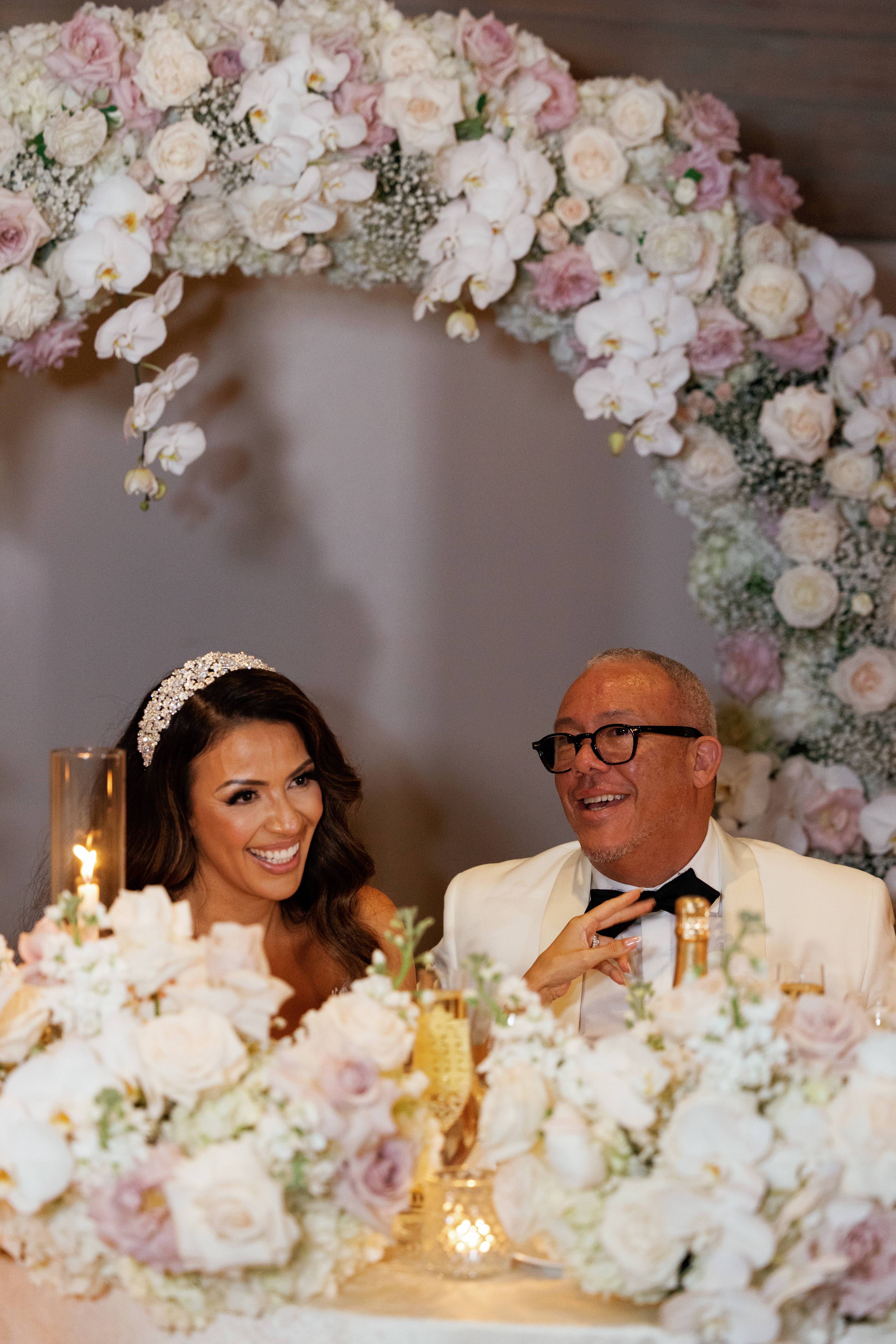 bride and groom seated under arch made from flowers
