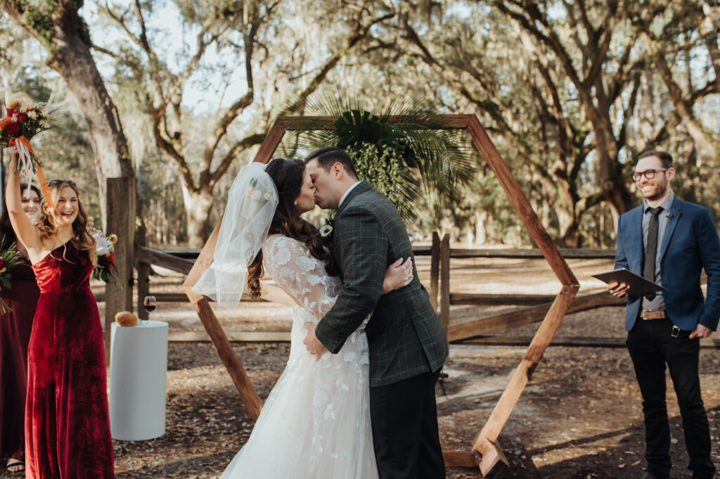 bride and groom in front of hexagon wooden wedding arch